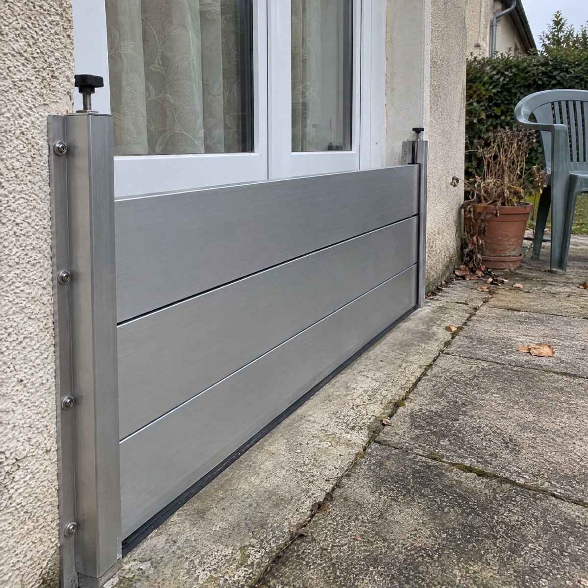 Détail des lames aluminium et du montant latéral d'un batardeau devant une porte-fenêtre